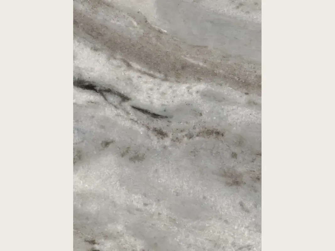 Placa de mármol gris Fantasy Brown: fondo gris claro, nubes blancas, franjas difusas en diagonal suave y trazos marrón grisáceo