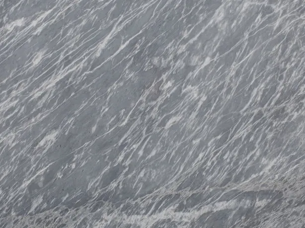 Detalle del Mármol Gris Perla: trazos blancos cortos y muy densos sobre el gris azulado, con el brillo del pulido