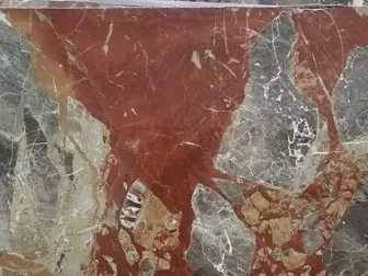 Detalle del Mármol Macchia Vecchia: mancha rojo óxido con fragmentos gris verdoso y el brillo del pulido