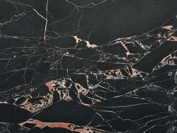 Detalle del Mármol Orange Black: manchas naranja salmón y vetas blancas finas sobre el negro pulido