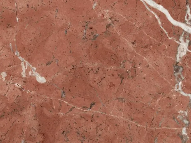 Detalle del Mármol Rojo Alicante: veta blanca en diagonal y motas oscuras sobre el rojo pulido