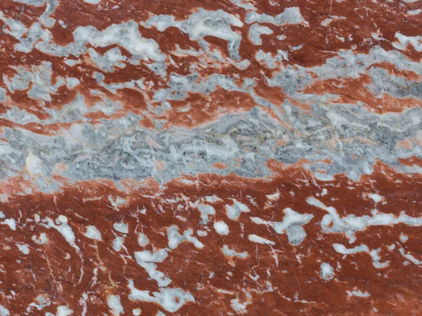 Detalle del Mármol Rojo Francia: bandeado apretado de rojo, gris azulado y blanco con brillo de pulido