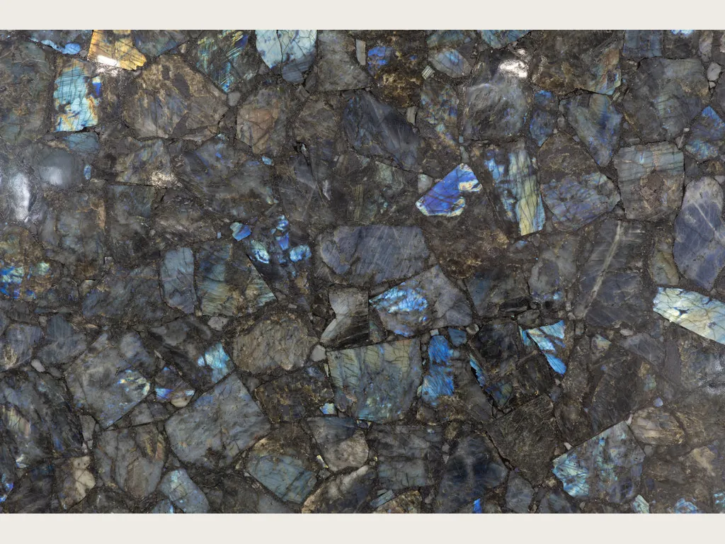 Placa de labradorita: mosaico de piezas grises con destellos azules iridiscentes
