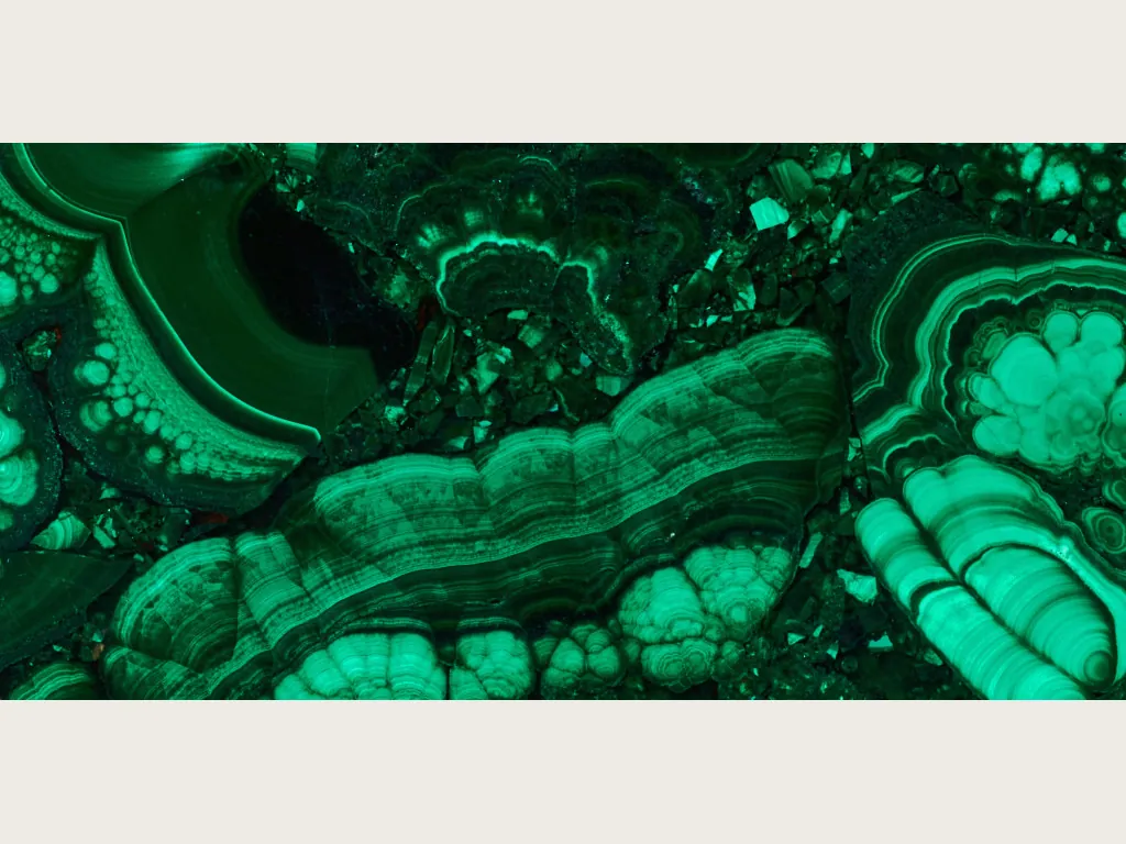 Placa de malaquita: bandas concéntricas verde claro y oscuro con círculos tipo ojo sobre verde esmeralda