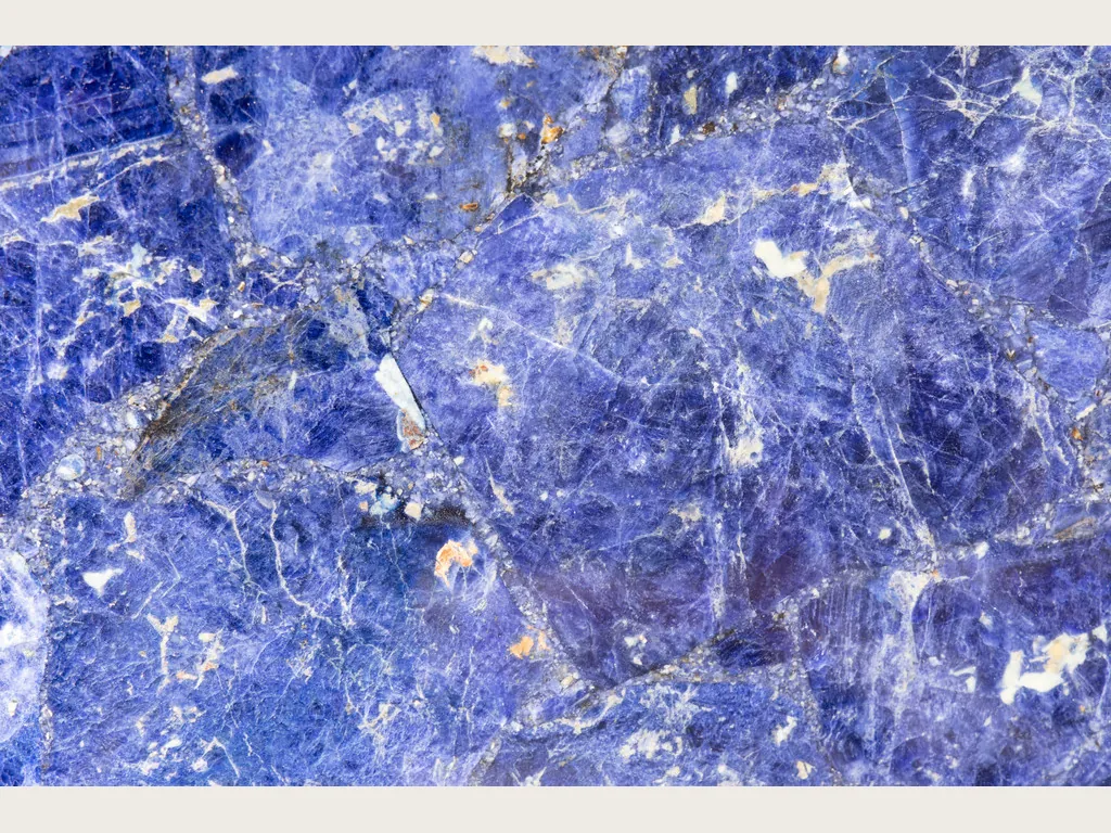 Placa de sodalita: azul violeta con vetas blancas irregulares y motas naranjas