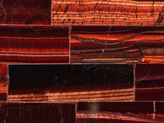 Detalle del Ojo de Tigre Rojo: bandas cobrizas y burdeos con el brillo cambiante del pulido