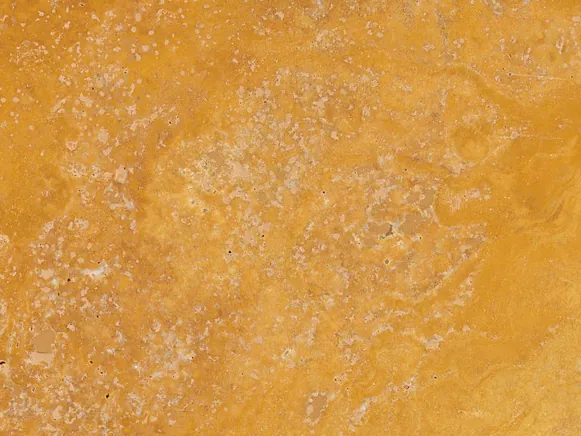 Detalle del Travertino Amarillo: poros pequeños y nubes de tono sobre el fondo dorado