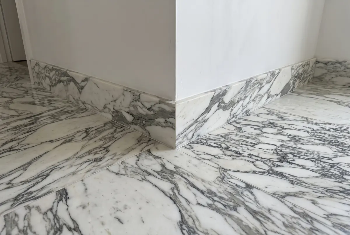 Zócalo de mármol Arabescato en la esquina de una pared, sobre un piso de la misma piedra