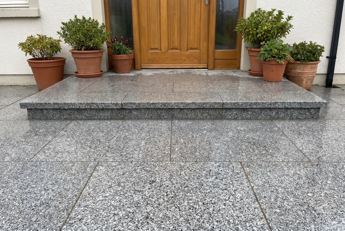 Entrada de casa con escalones y piso exterior de granito gris flameado