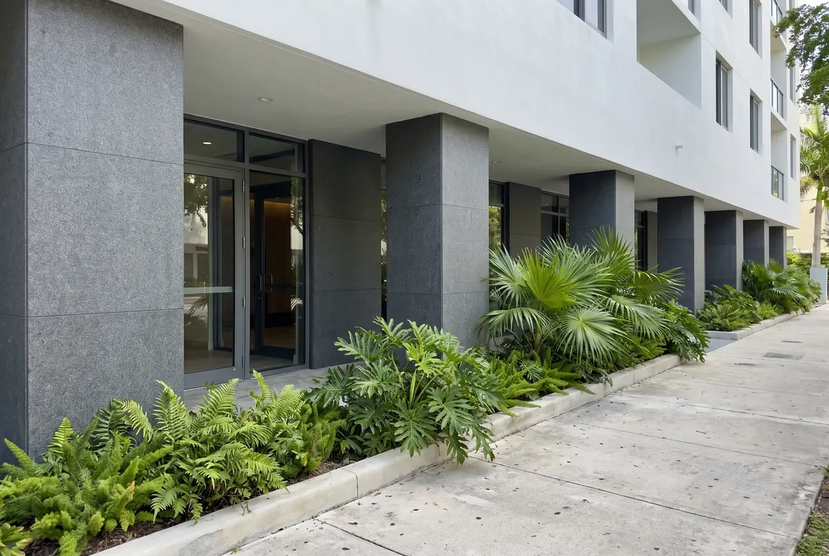 Planta baja de un edificio con columnas y base de fachada revestidas en granito gris oscuro