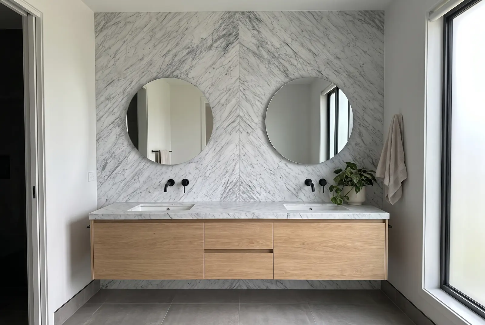 Baño con la pared del lavabo en dos placas de Mármol Carrara colocadas en libro y mueble de roble